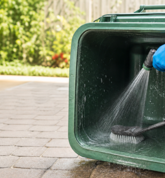 Cleaning an outdoor trash can with gloves and a scrub brush