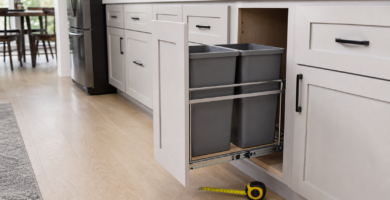Pull-out trash can system extended from a kitchen cabinet with measuring tape